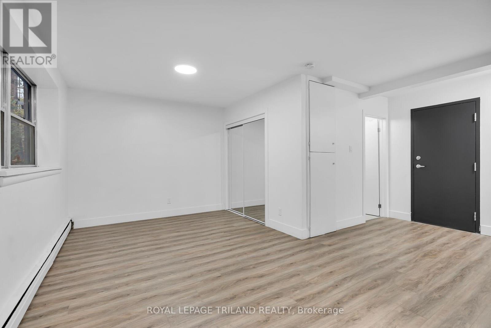 A white room with wooden flooring and a black door.