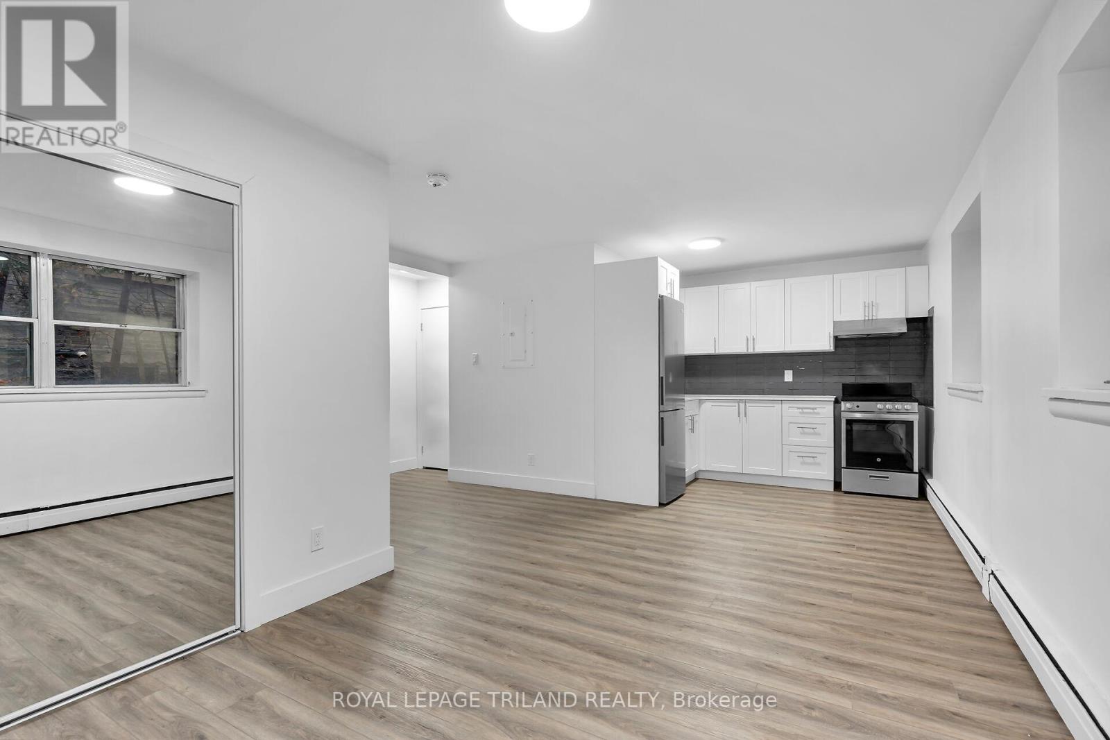 A spacious, empty room with wooden flooring and white walls.