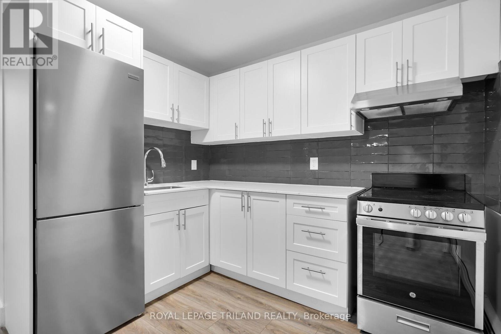 A modern kitchen with white cabinets and a stainless steel refrigerator.