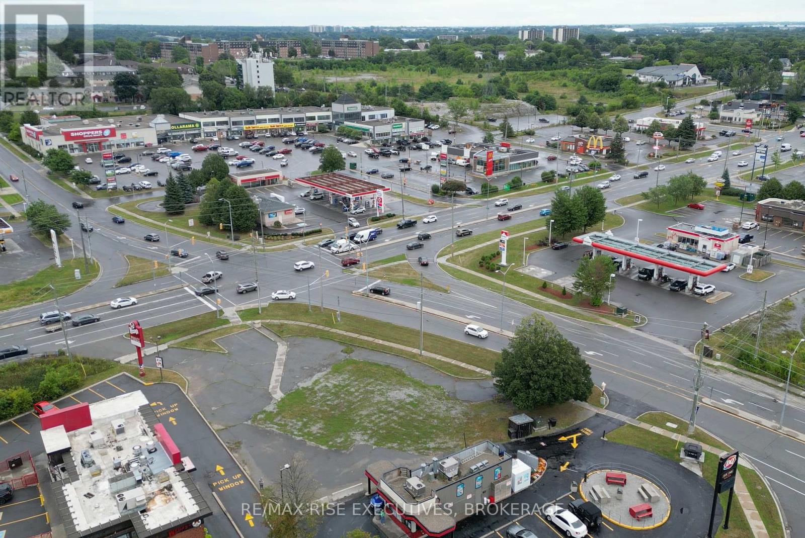 A busy intersection with a RE/MAX Rise Excellence Brokerage sign in the parking lot.