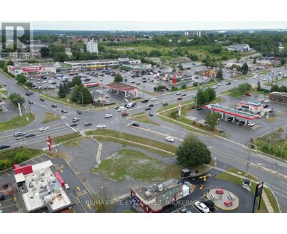 A busy intersection with a RE/MAX Rise Excellence Brokerage sign in the parking lot.