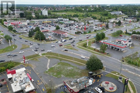 A busy intersection with a RE/MAX Rise Excellence Brokerage sign in the parking lot.