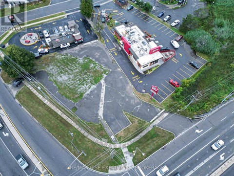 A parking lot with a building and a grassy area in the middle.