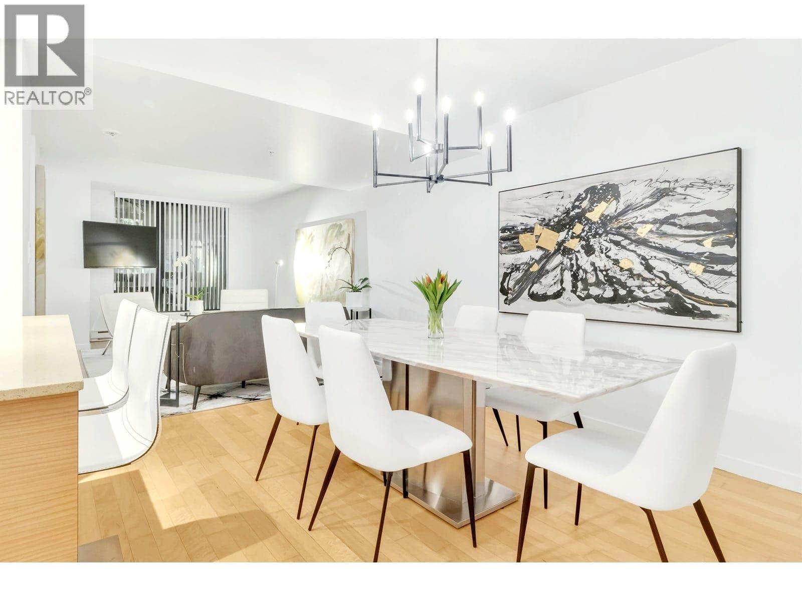 A modern dining room with a glass table and white chairs.