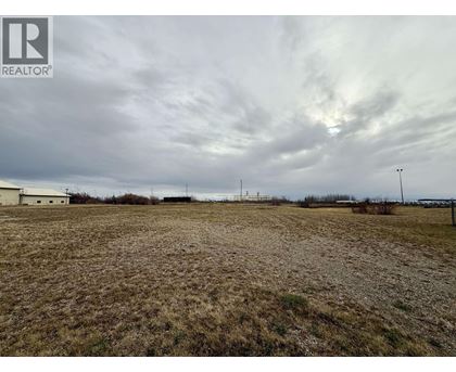 A field with a cloudy sky and a building in the distance.