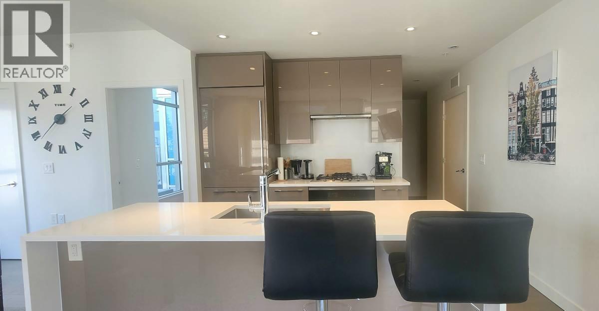 A modern kitchen with a large island and two chairs.