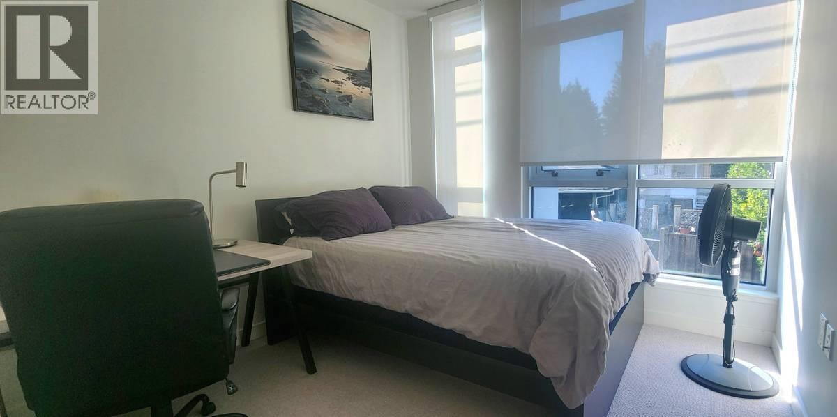 A bedroom with a bed, desk, chair, and window.