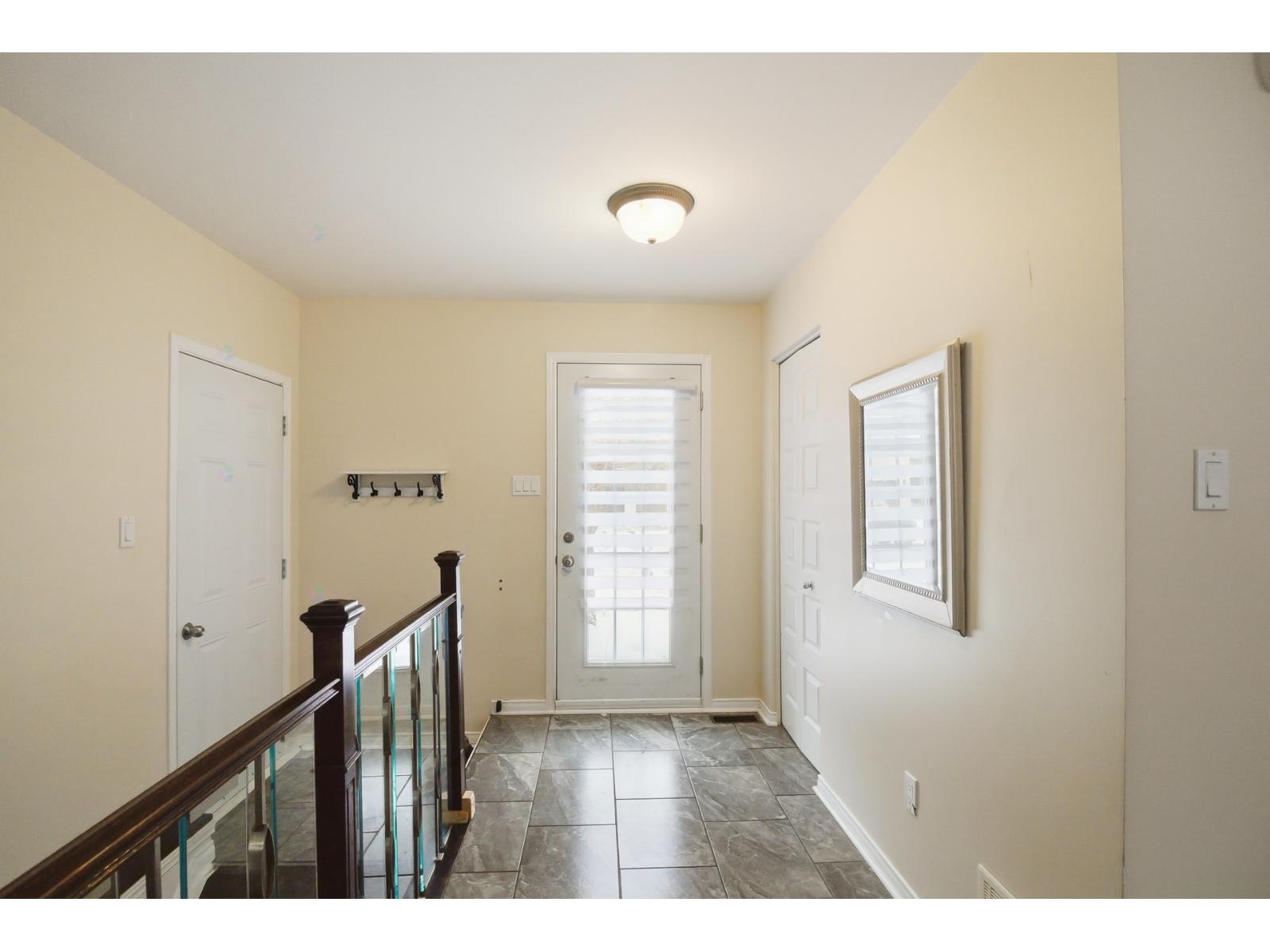 A hallway with a glass railing and a tiled floor.
