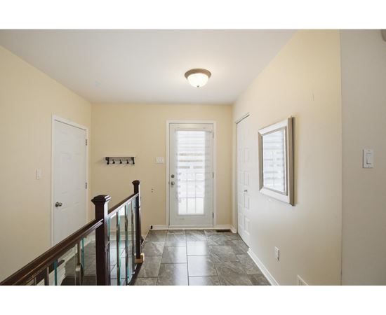 A hallway with a glass railing and a tiled floor.