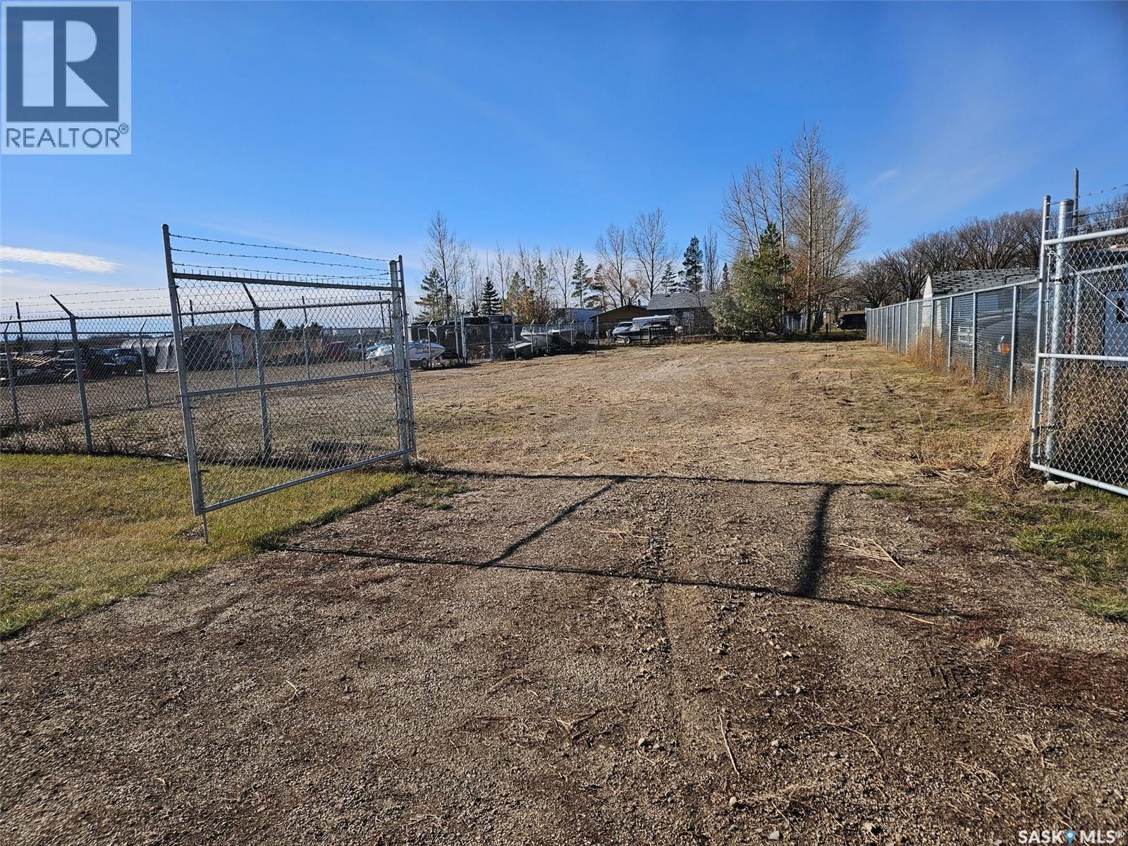 A large, empty plot of land is fenced in and ready for development.