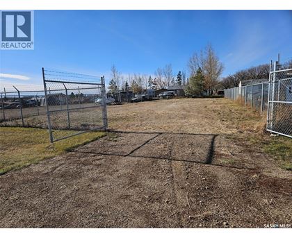 A large, empty plot of land is fenced in and ready for development.