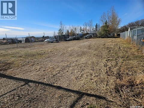 A large, empty field with a fence and some trees in the distance.