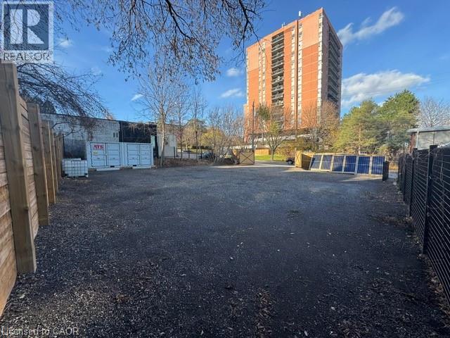 A gravel lot with a fence and a building in the background.