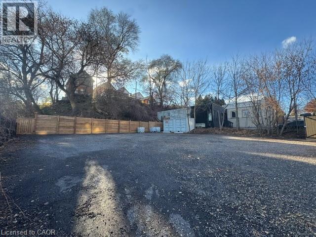 A gravel lot with a fence and trees in the background.