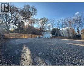 A gravel lot with a fence and trees in the background.