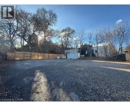 A gravel lot with a fence and trees in the background.