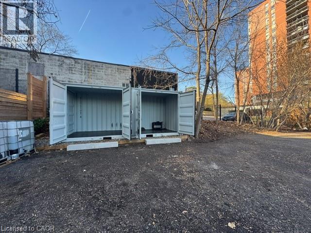 A large grey shipping container sits in a gravel lot.