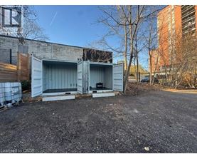 A large grey shipping container sits in a gravel lot.