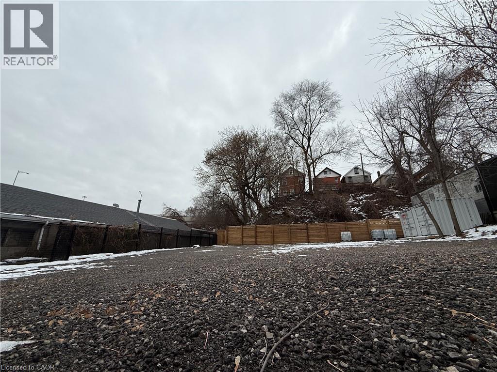 A gravel lot with a fence and houses in the background.
