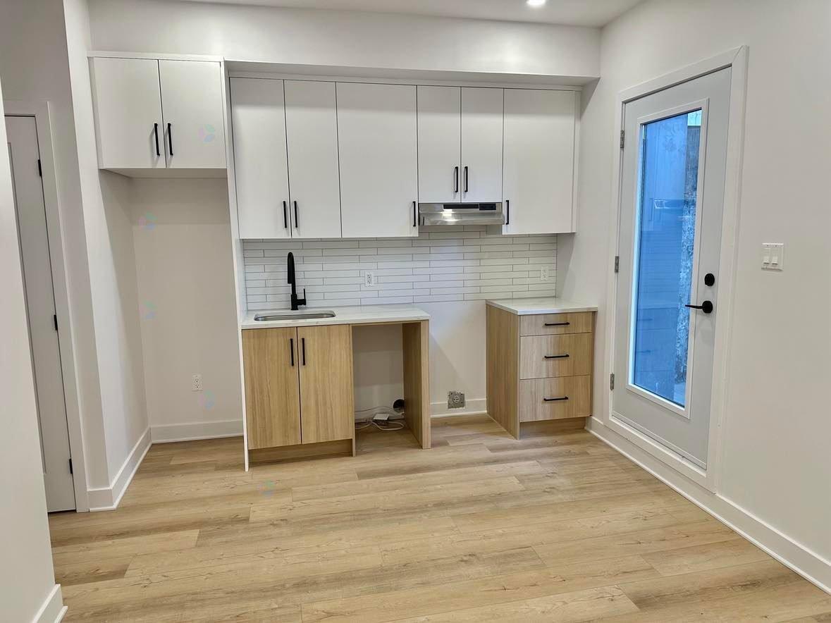 A kitchen with white cabinets and a wooden floor.