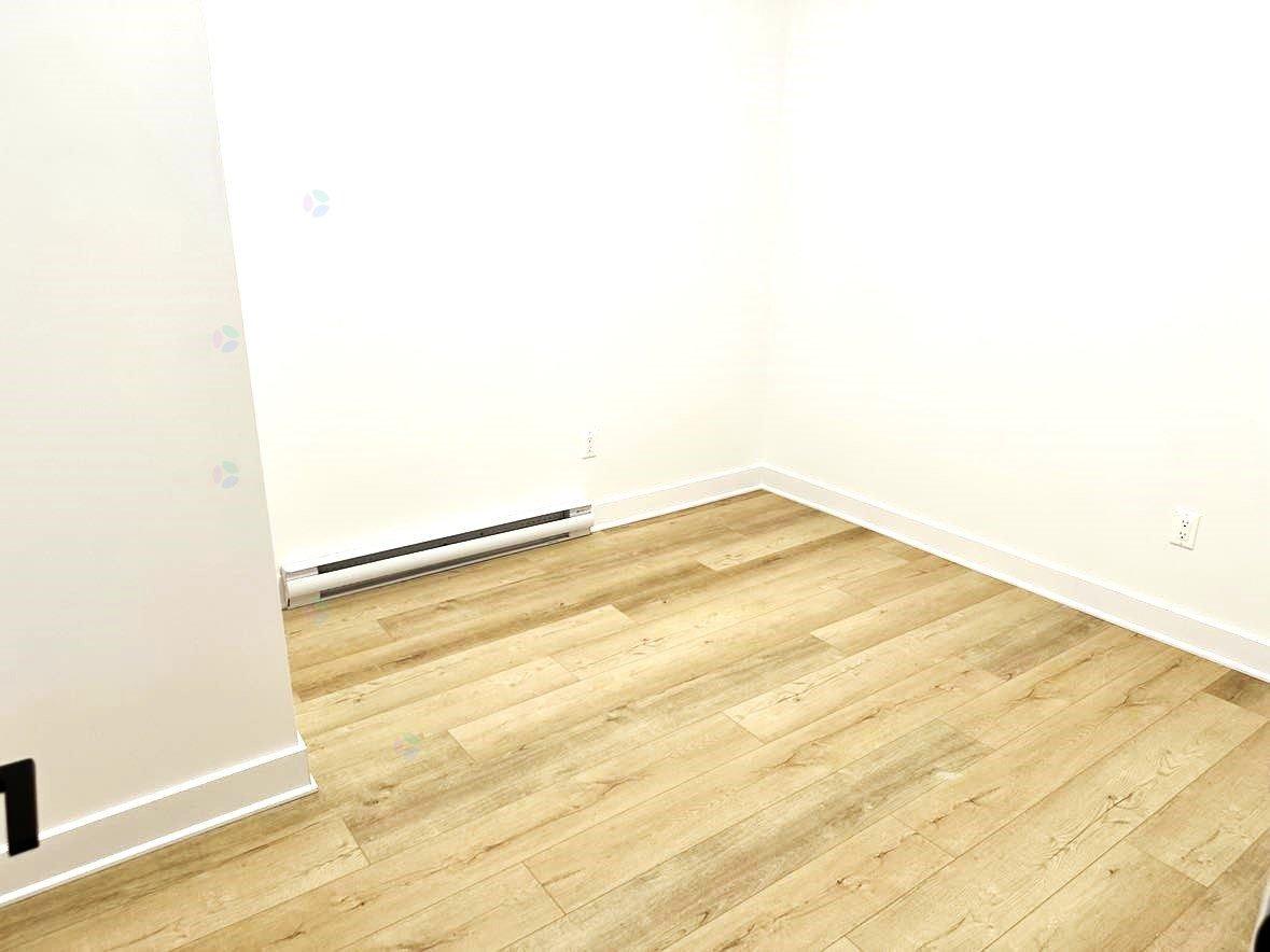 A room with wooden flooring and white walls.