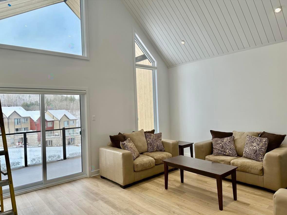 A living room with a couch, a coffee table, and a large window.