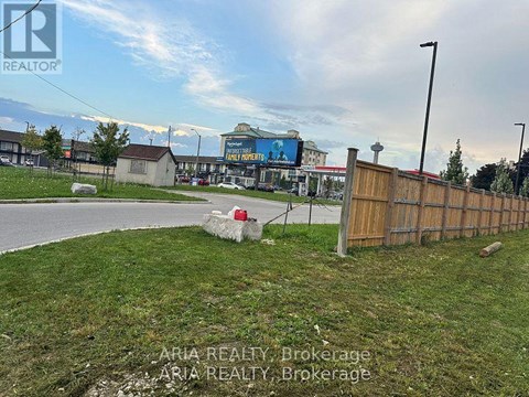 A grassy area with a fence and a sign that says "REALTOR".