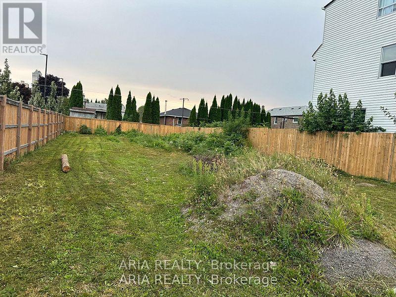 A backyard with a fence and a grassy area.