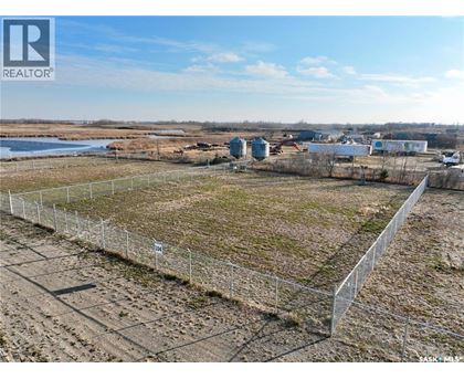 A fenced-off plot of land with a building in the distance.