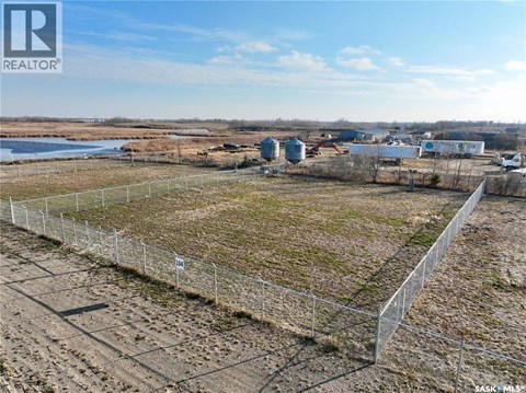 A fenced-off plot of land with a building in the distance.