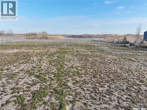 A field with a fence and a body of water in the distance.