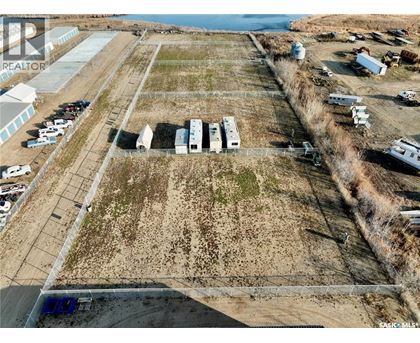 A large open field with a few buildings and vehicles.