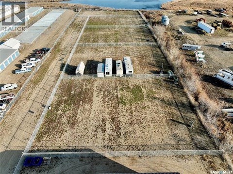 A large open field with a few buildings and vehicles.