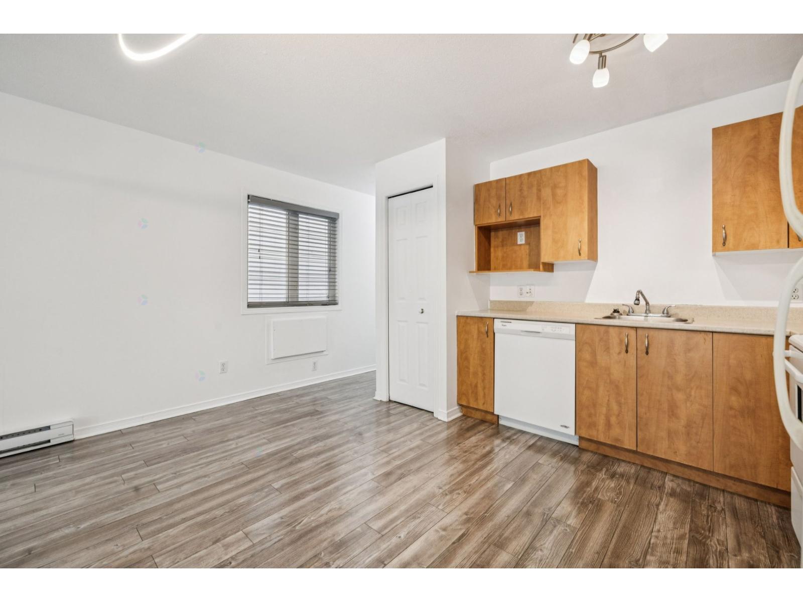 A kitchen with wooden cabinets and a white dishwasher.