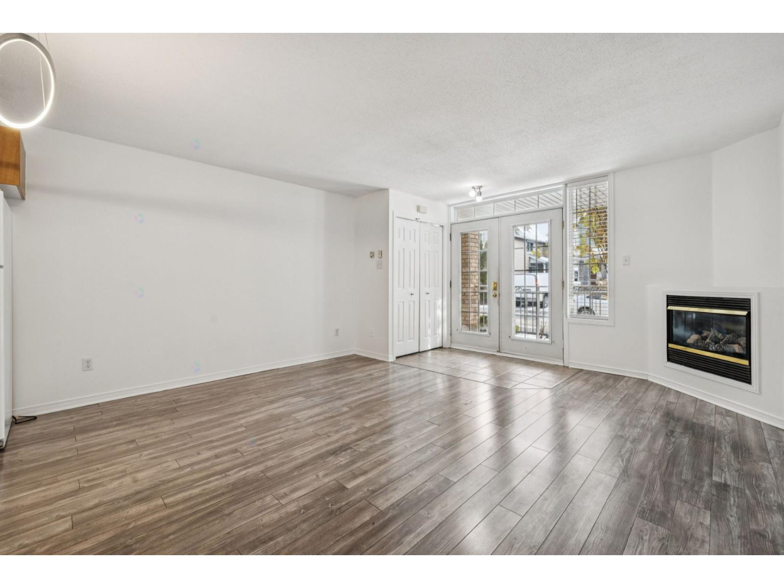 A spacious living room with a fireplace and wood flooring.