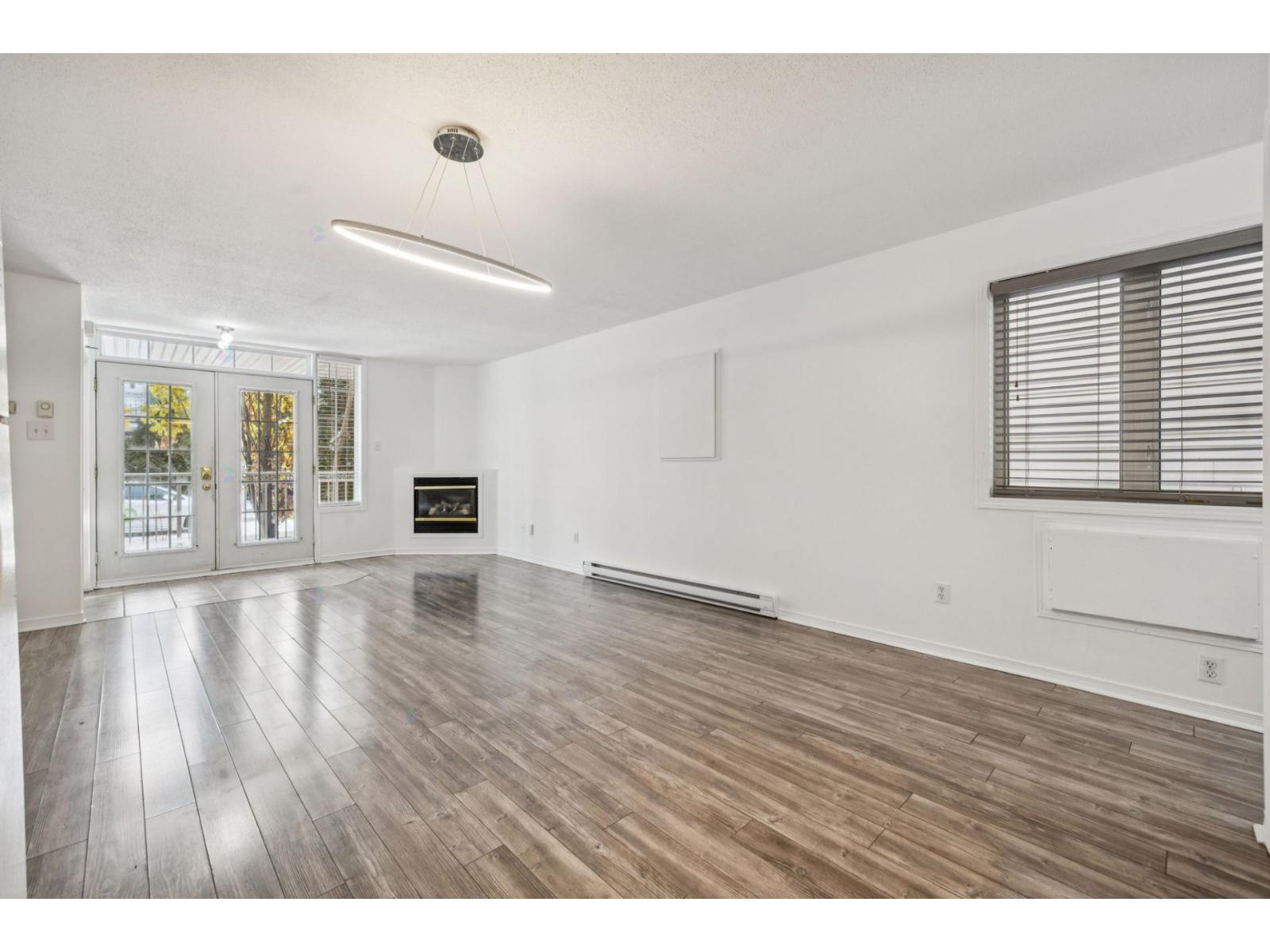 A spacious room with wooden flooring and a fireplace.