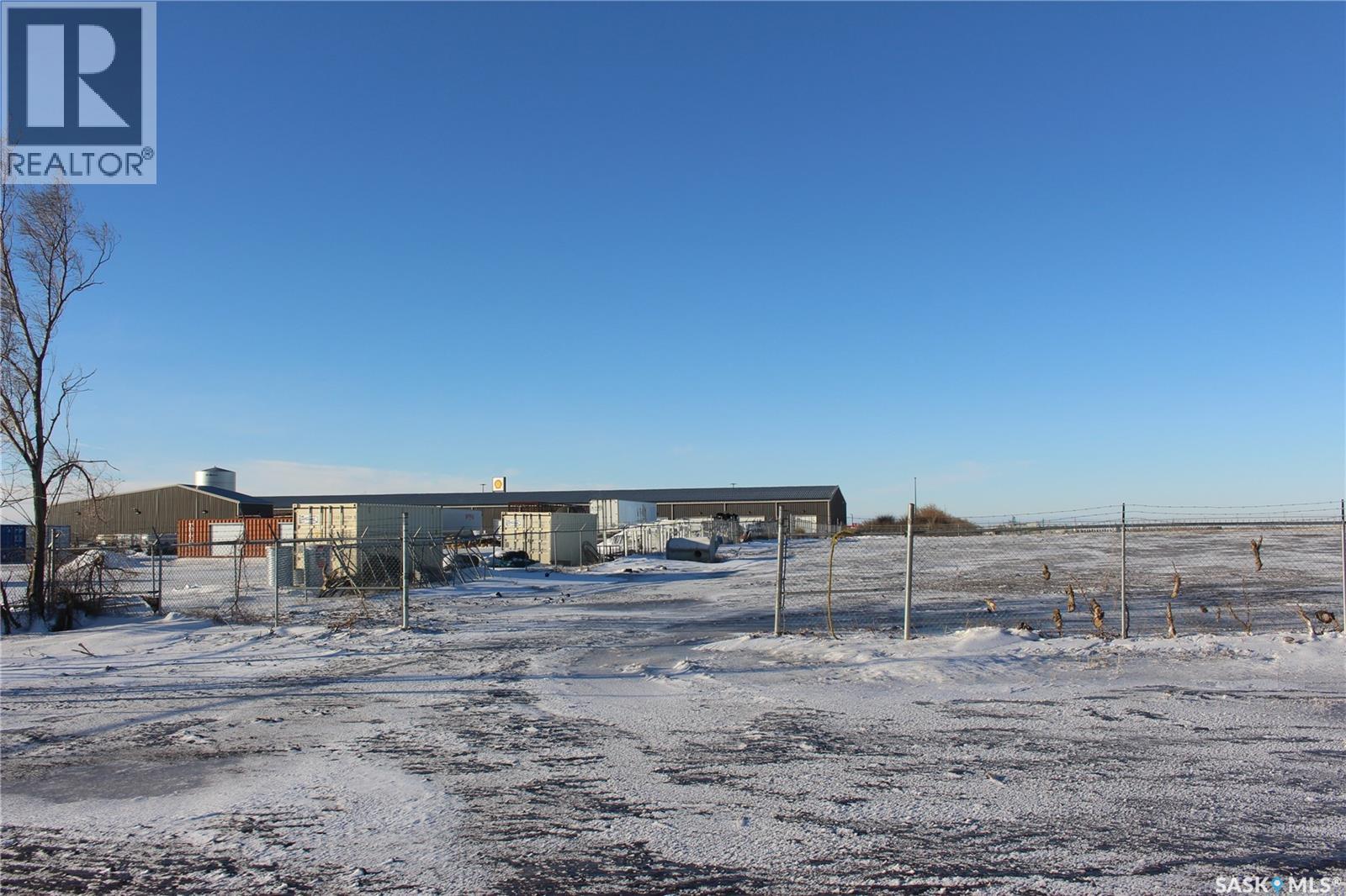 A snowy field with a building and a fence in the background.