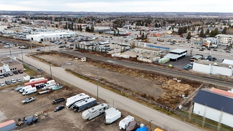 A large parking lot with several vehicles and buildings in the distance.