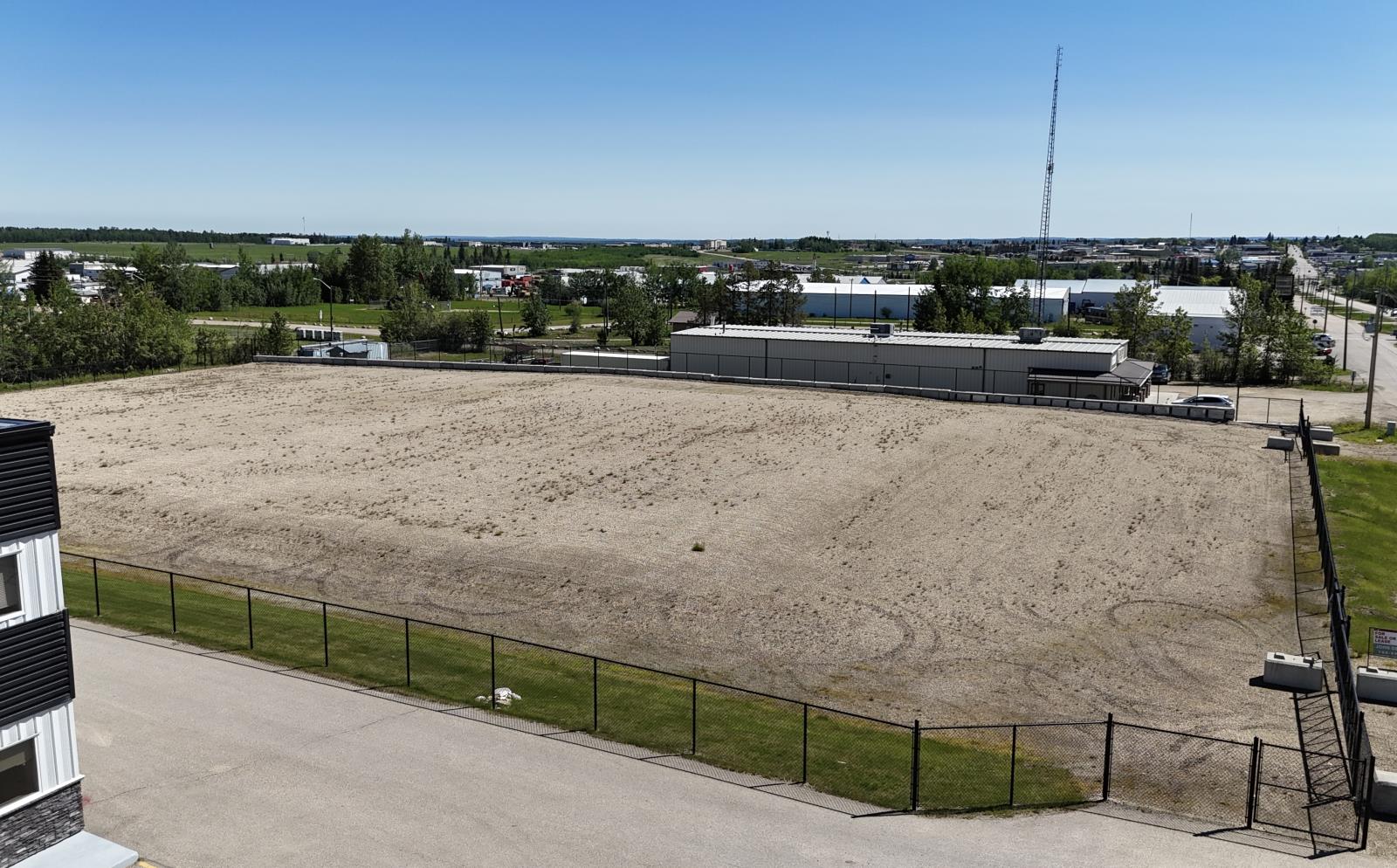 A large, empty field with a fence and a building in the background.