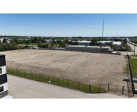 A large, empty field with a fence and a building in the background.