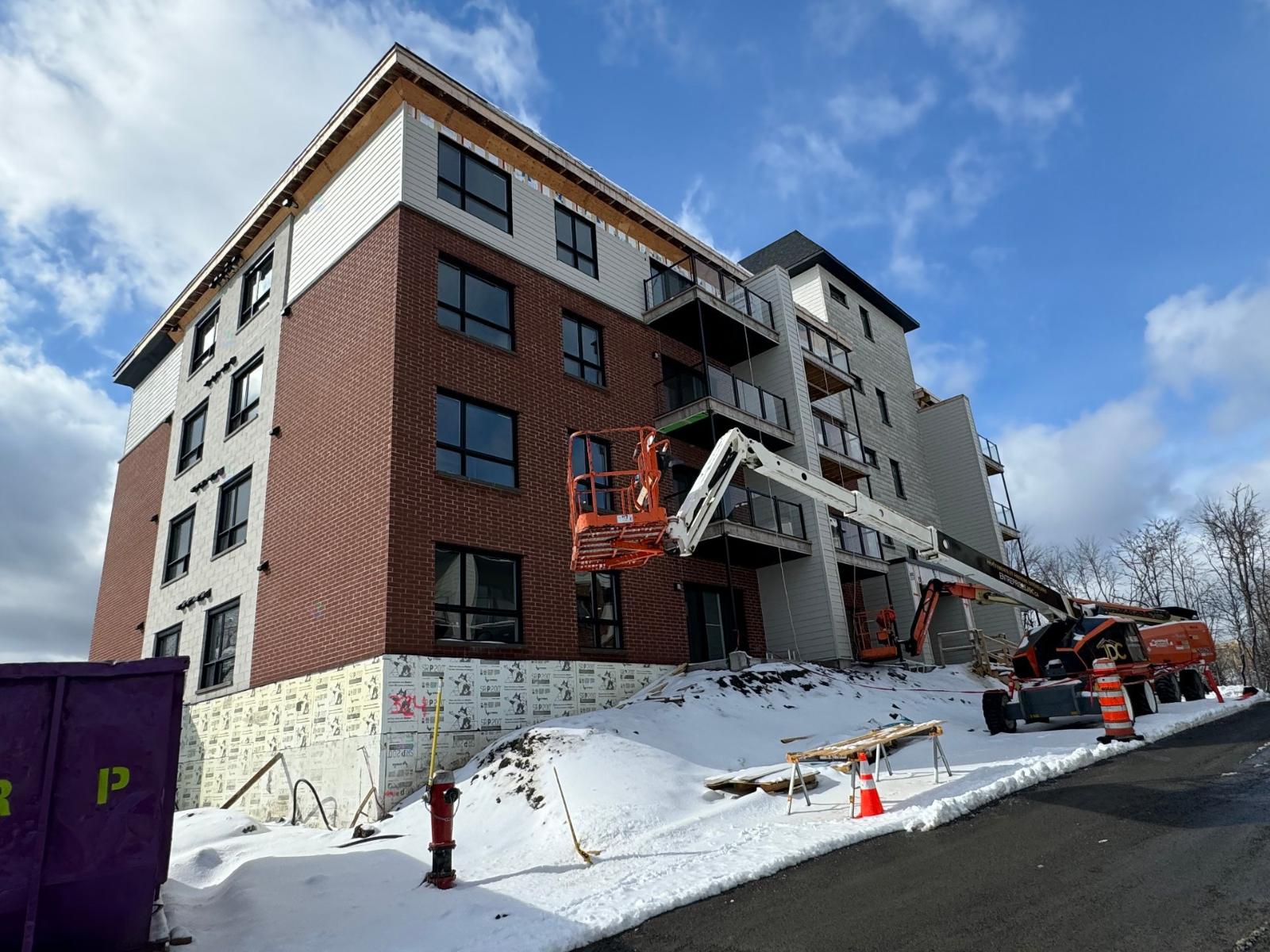 A building under construction with a crane and orange cones around it.