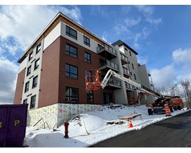 A building under construction with a crane and orange cones around it.