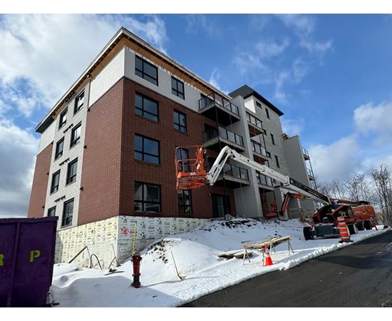 A building under construction with a crane and orange cones around it.