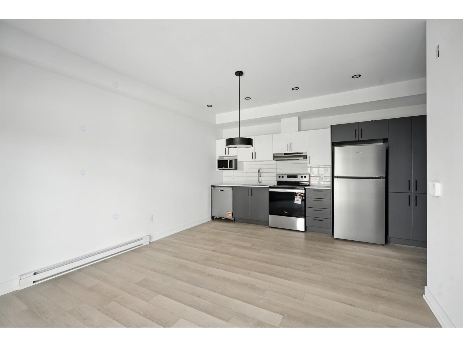 A modern kitchen with stainless steel appliances and wooden flooring.