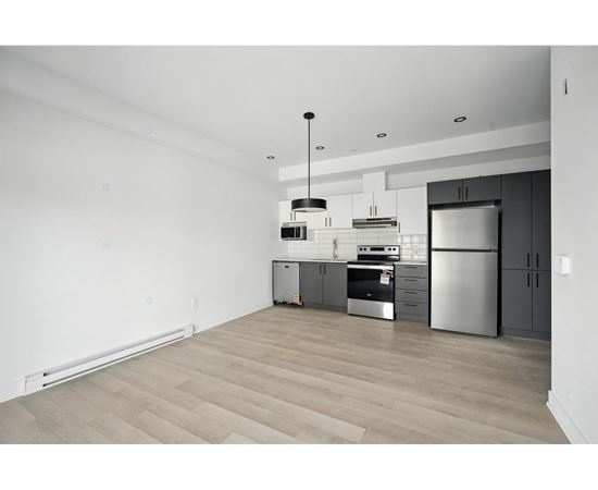 A modern kitchen with stainless steel appliances and wooden flooring.
