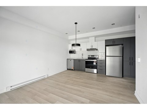A modern kitchen with stainless steel appliances and wooden flooring.
