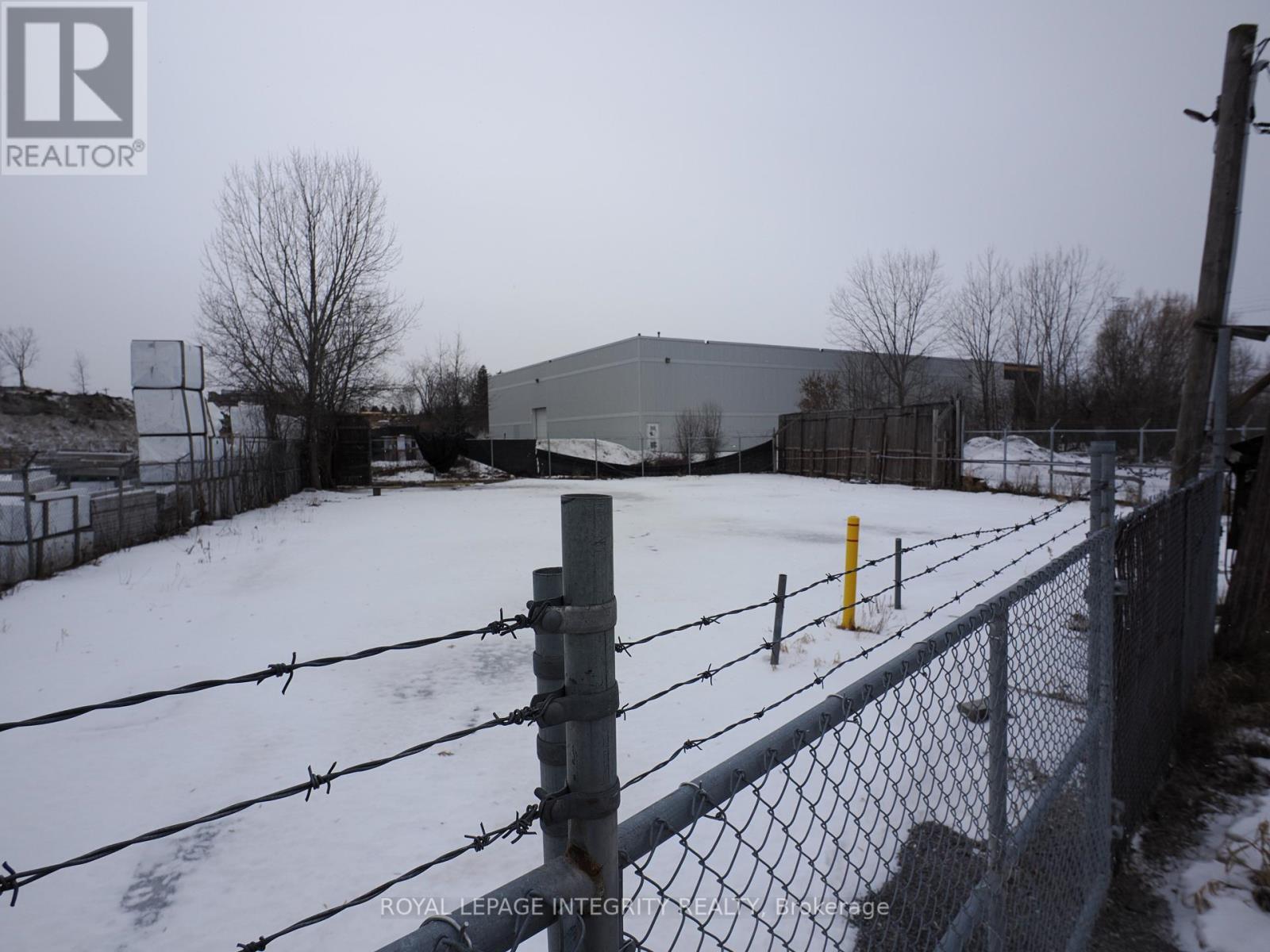A snow-covered field with a fence and a building in the background.