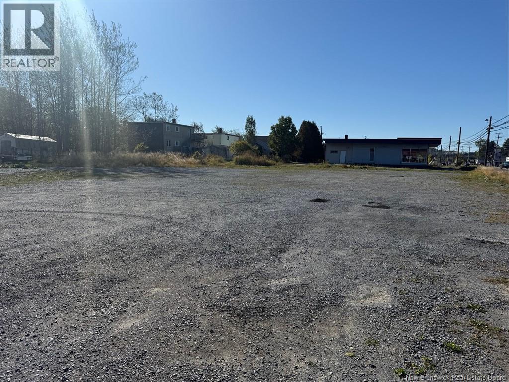 A gravel lot with a building in the background and a logo in the upper left corner.