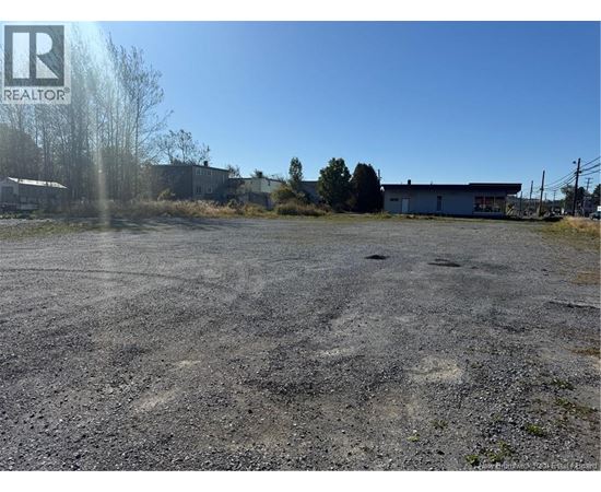 A gravel lot with a building in the background and a logo in the upper left corner.