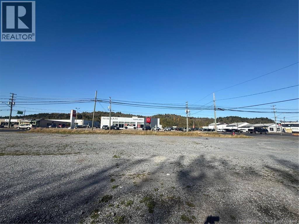 A gravel lot with a building in the background and power lines above.